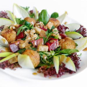 Frischer Falafel-Salat mit knusprigen Kichererbsenbällchen, bunten Blattsalaten, Radicchio, Rote-Bete-Würfeln und Dressing in einer weißen Schüssel.