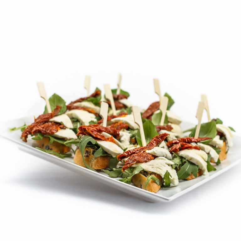 Crostini mit getrockneten Tomaten, Mozzarella, Basilikumpesto und Rucola von ehab Catering