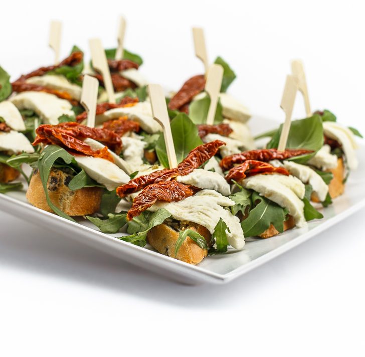 Crostini mit getrockneten Tomaten, Mozzarella, Basilikumpesto und Rucola von ehab Catering